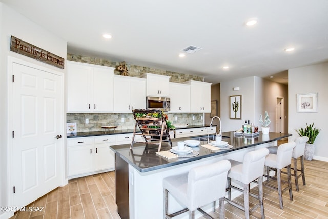 kitchen with appliances with stainless steel finishes, a breakfast bar, white cabinetry, sink, and a kitchen island with sink