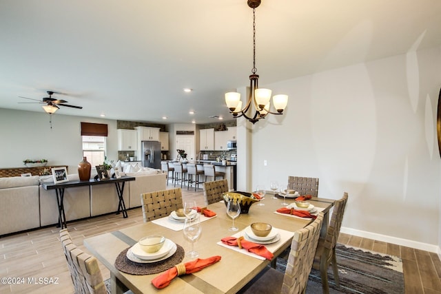 dining space featuring ceiling fan with notable chandelier