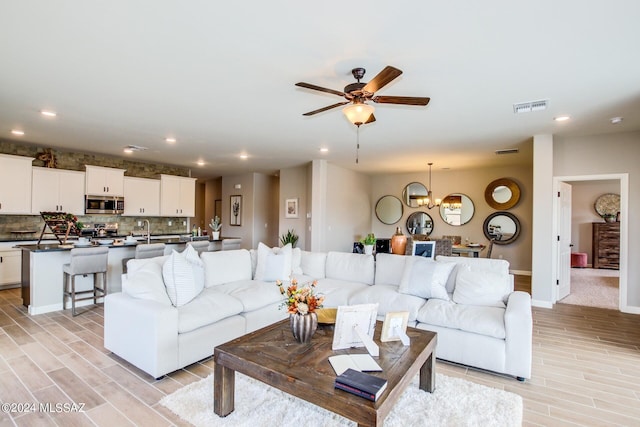 living room with sink and ceiling fan with notable chandelier