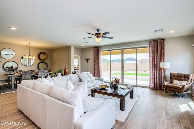 living room featuring a mountain view, ceiling fan with notable chandelier, and light wood-type flooring