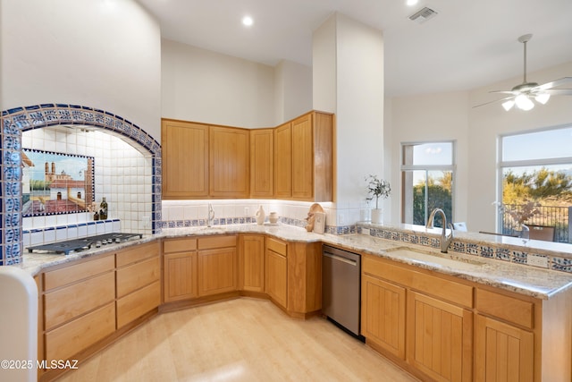 kitchen featuring tasteful backsplash, sink, stainless steel appliances, light stone countertops, and light hardwood / wood-style flooring