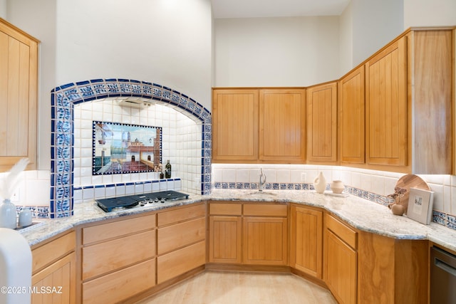 kitchen featuring tasteful backsplash, sink, light stone counters, and stainless steel appliances