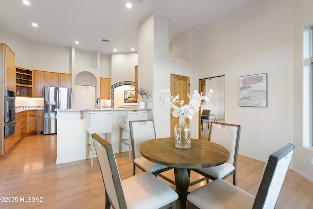 dining space with light hardwood / wood-style flooring and a high ceiling