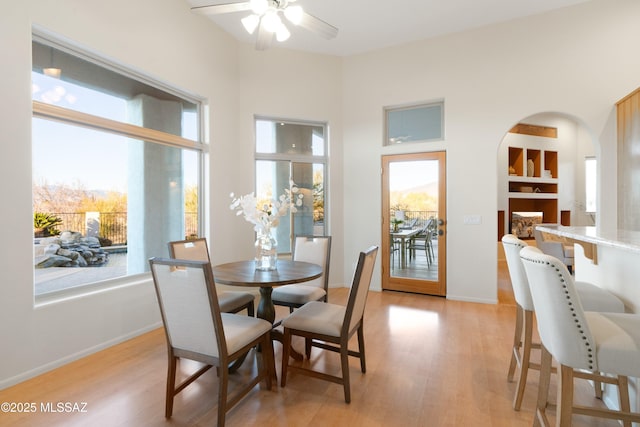 dining room featuring built in shelves, ceiling fan, a healthy amount of sunlight, and light hardwood / wood-style floors