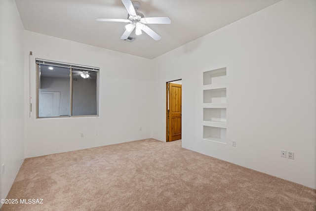 carpeted spare room with ceiling fan and built in features