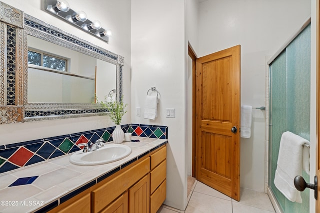 bathroom with tile patterned floors, vanity, a shower with shower door, and decorative backsplash