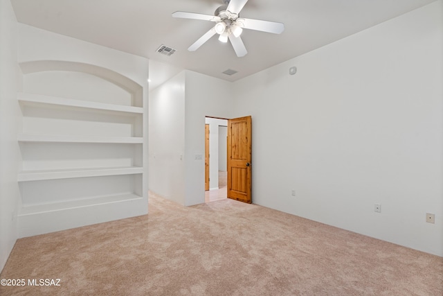 carpeted empty room with built in features and ceiling fan