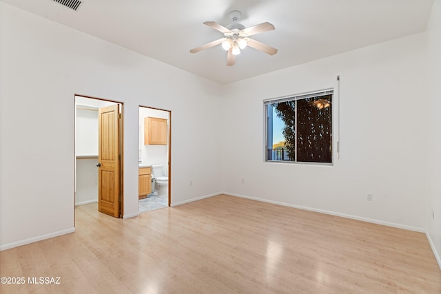 unfurnished bedroom with connected bathroom, a spacious closet, ceiling fan, light wood-type flooring, and a closet