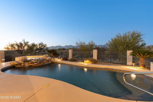 pool at dusk featuring a mountain view