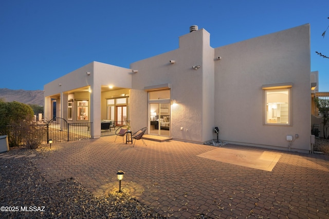 back house at dusk featuring a mountain view and a patio area