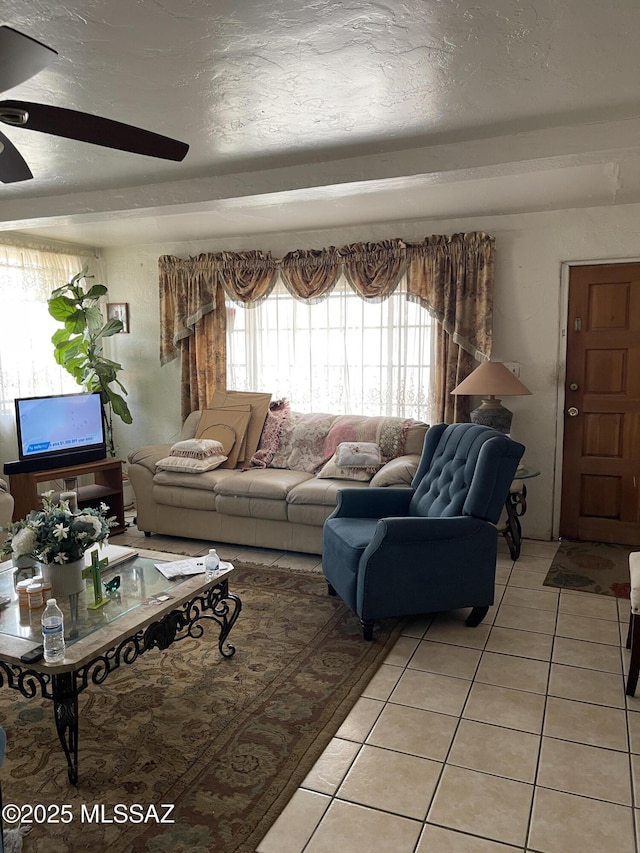 living room with a ceiling fan, a textured ceiling, and light tile patterned flooring