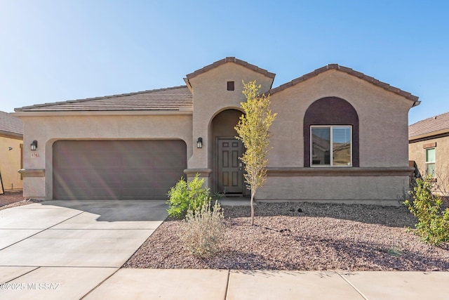 mediterranean / spanish-style home with a tile roof, stucco siding, an attached garage, and concrete driveway