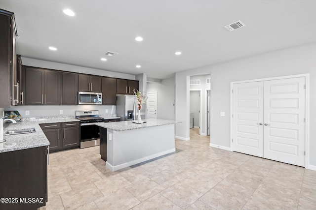 kitchen with a center island, appliances with stainless steel finishes, a sink, and visible vents