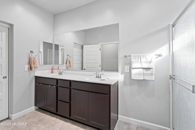 full bath with a sink, baseboards, and double vanity