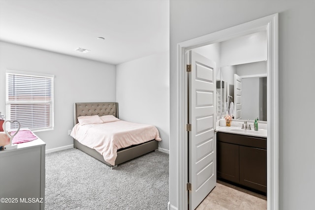 bedroom featuring connected bathroom, light colored carpet, baseboards, and a sink