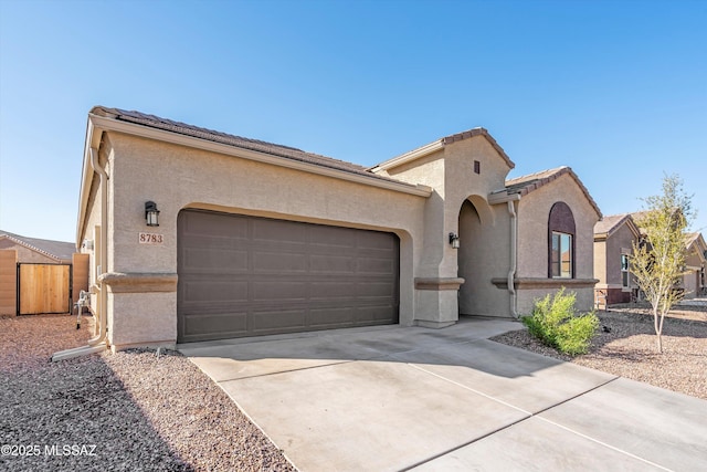 mediterranean / spanish-style home with stucco siding, concrete driveway, an attached garage, and a tile roof