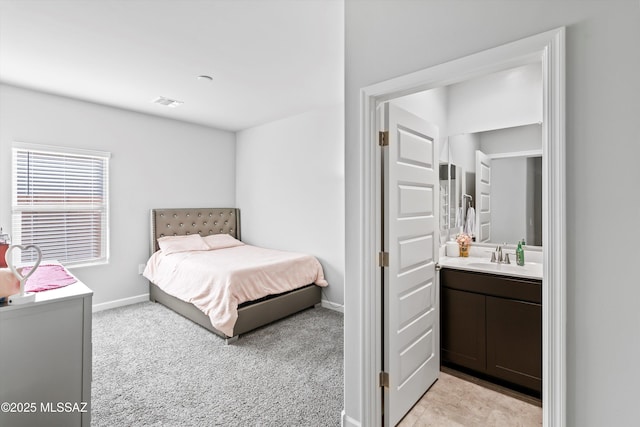 bedroom featuring light carpet, ensuite bathroom, baseboards, and a sink