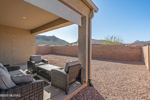 view of patio with an outdoor living space, a mountain view, and a fenced backyard