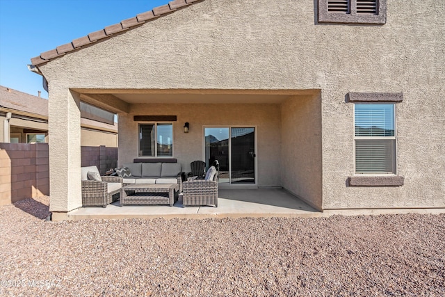 rear view of house featuring an outdoor living space, stucco siding, and a patio