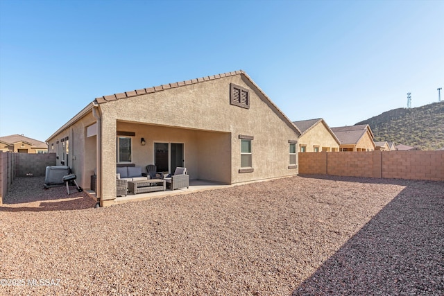 rear view of house with stucco siding, a patio, a fenced backyard, and an outdoor hangout area