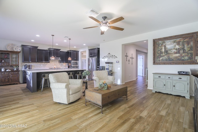 living room with light hardwood / wood-style floors and ceiling fan