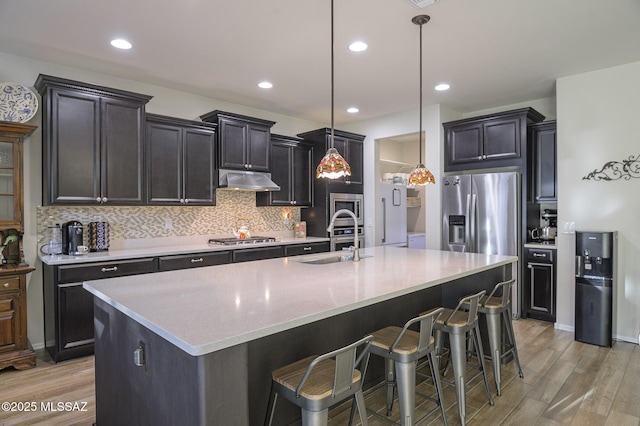 kitchen featuring pendant lighting, stainless steel appliances, sink, and a center island with sink