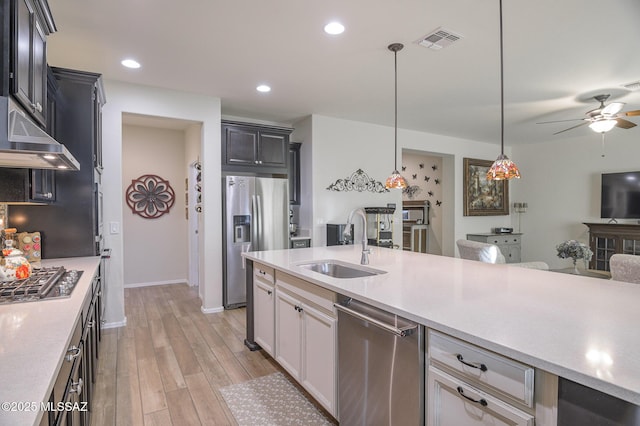 kitchen with sink, decorative light fixtures, light wood-type flooring, appliances with stainless steel finishes, and white cabinets