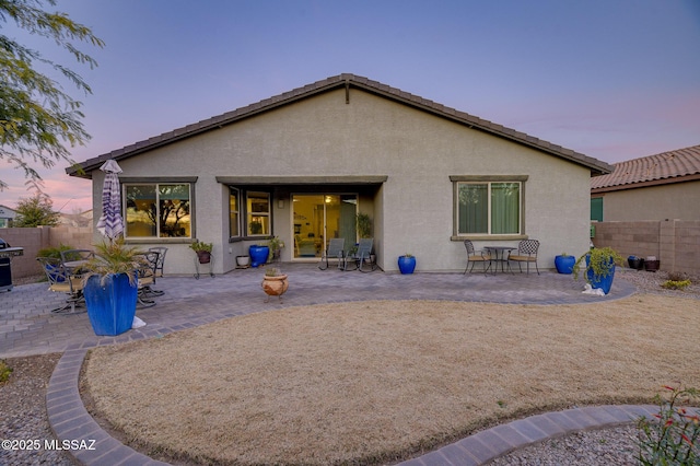 back house at dusk featuring a patio