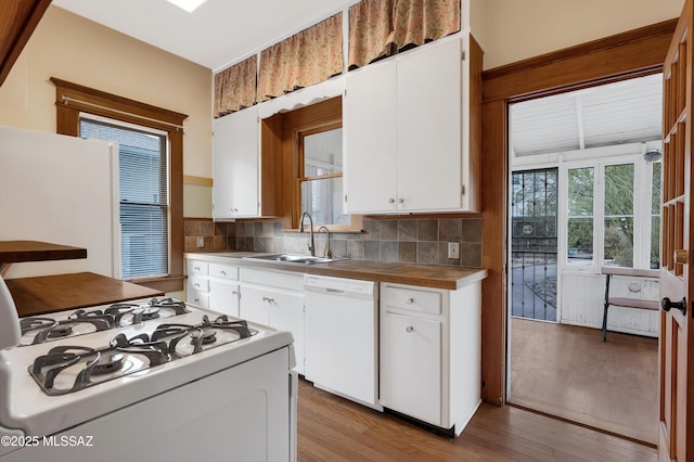 kitchen featuring white cabinetry, sink, light wood-type flooring, backsplash, and white appliances