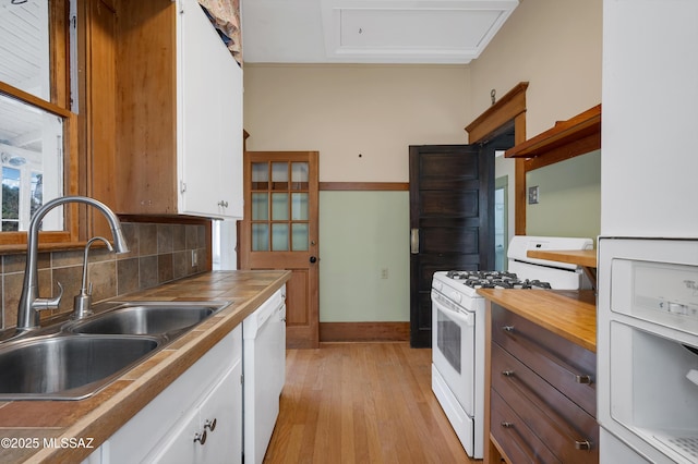 kitchen with tasteful backsplash, sink, light wood-type flooring, white cabinets, and white appliances