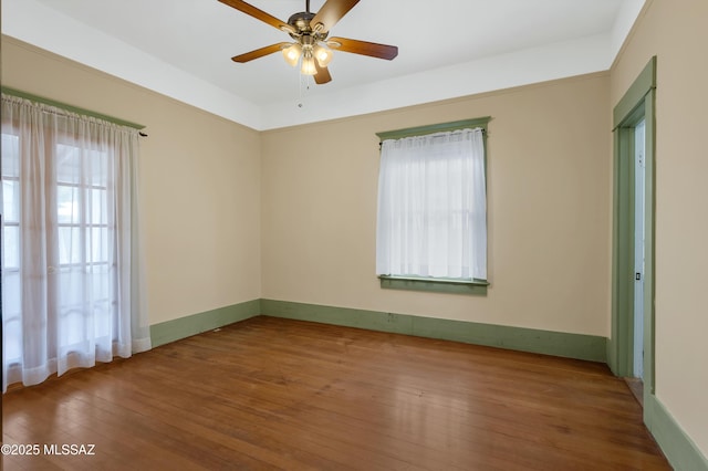 empty room featuring ceiling fan, plenty of natural light, and hardwood / wood-style floors