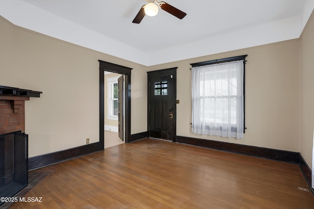 entrance foyer with dark hardwood / wood-style flooring, a fireplace, a wealth of natural light, and ceiling fan