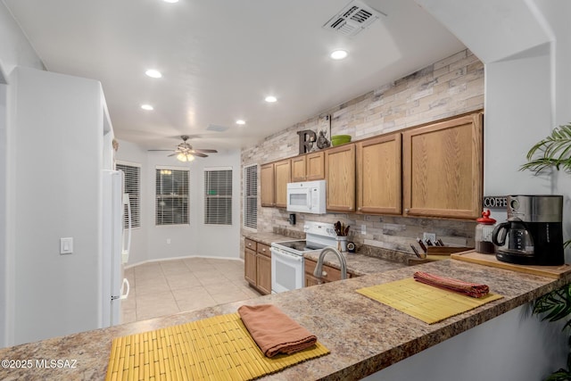 kitchen with white appliances, kitchen peninsula, light tile patterned floors, and backsplash