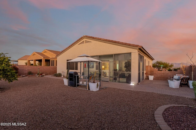 back house at dusk featuring a gazebo and a patio area