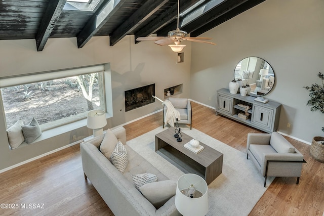 living room with wood ceiling, lofted ceiling with skylight, ceiling fan, and light wood-type flooring