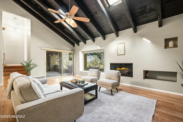 living room featuring ceiling fan, high vaulted ceiling, a multi sided fireplace, wood-type flooring, and beamed ceiling