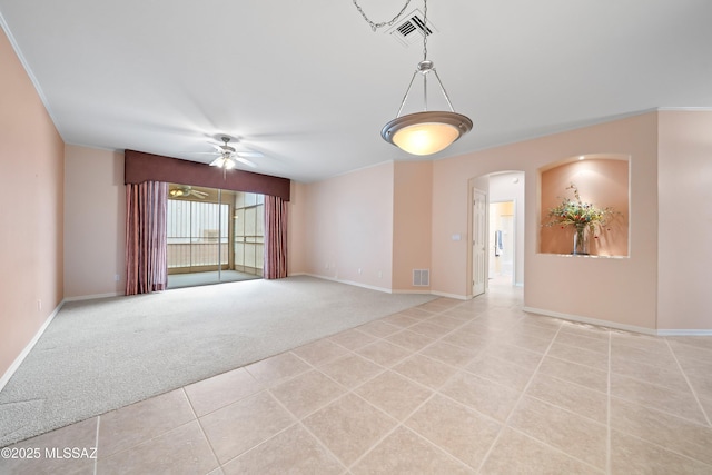 empty room with a ceiling fan, light colored carpet, visible vents, and baseboards