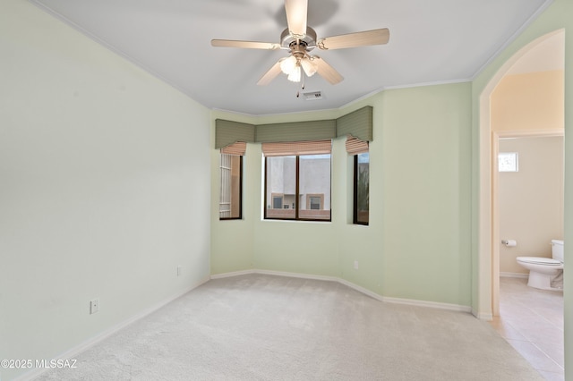 interior space featuring visible vents, arched walkways, crown molding, carpet floors, and multiple windows