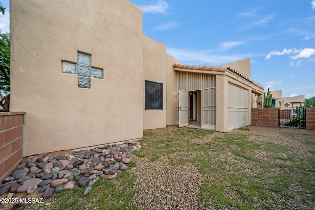 back of property with fence, a tiled roof, and stucco siding