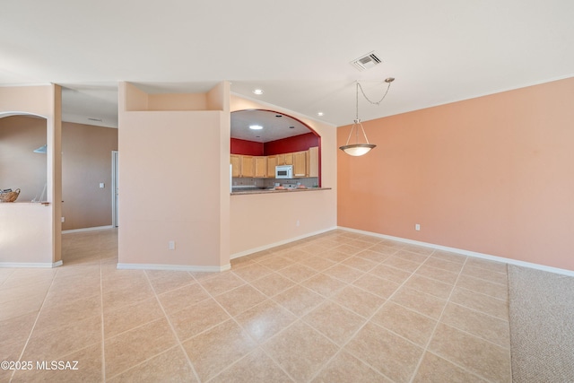 spare room with light tile patterned floors, baseboards, visible vents, arched walkways, and recessed lighting