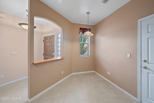 spare room with baseboards, visible vents, arched walkways, and light tile patterned flooring