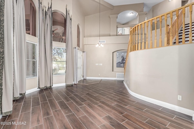 foyer entrance with baseboards, visible vents, a towering ceiling, and wood finish floors