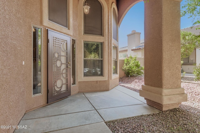 entrance to property featuring a patio and stucco siding