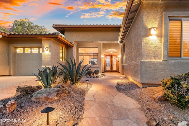 view of front of house with driveway, an attached garage, and stucco siding