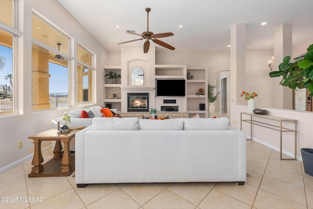 living room with light tile patterned floors, arched walkways, a glass covered fireplace, and recessed lighting