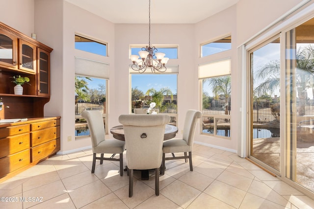 dining space featuring baseboards, a notable chandelier, light tile patterned flooring, and a towering ceiling