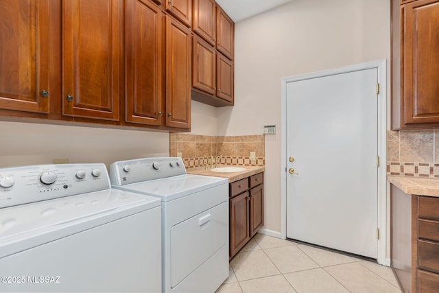 clothes washing area featuring light tile patterned flooring, a sink, cabinet space, and separate washer and dryer