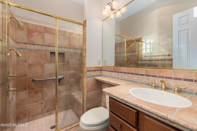 full bath featuring a shower stall, vanity, tile walls, and toilet