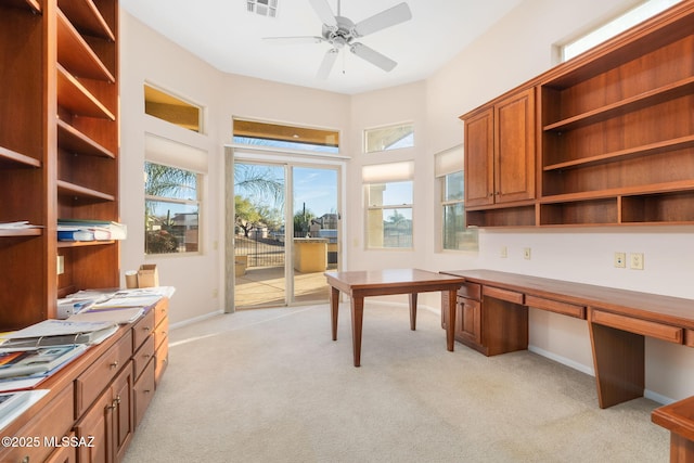 home office with baseboards, visible vents, ceiling fan, built in desk, and light carpet