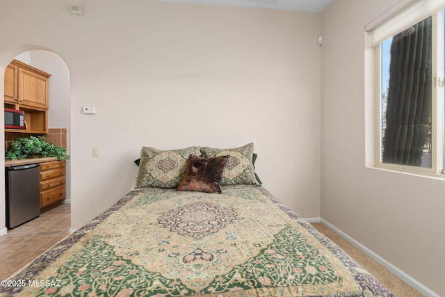 bedroom featuring fridge and baseboards